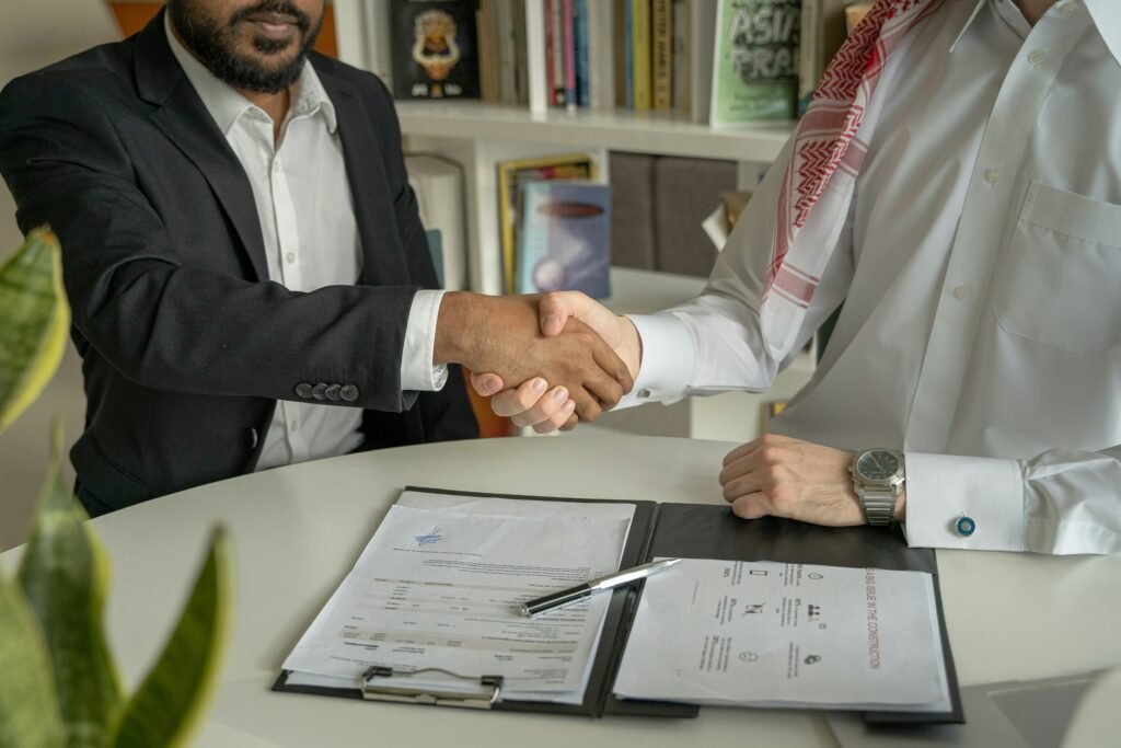 Business professionals shaking hands over documents, representing partnership and trade colaboration between Europe and Asia
